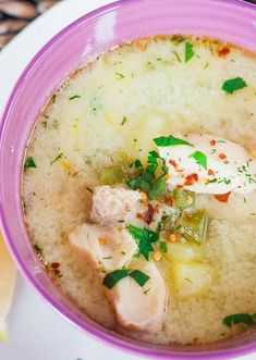 a purple bowl filled with soup on top of a white plate next to lemon wedges