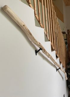 a wooden handrail on the side of a white wall next to a stair case