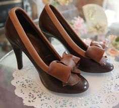 a pair of brown high heeled shoes on top of a doily covered table