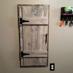 a wooden door is hanging on the wall next to a shelf with keys and other items