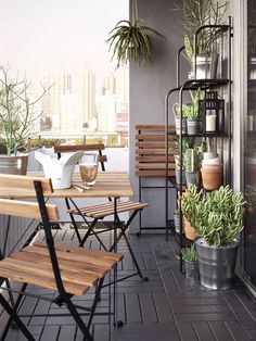 a balcony with wooden chairs and plants on the table, next to an open door