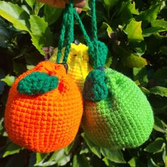 two crocheted oranges hanging from a tree