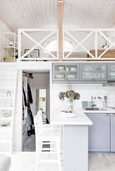 an open kitchen and living area with stairs leading up to the upper floor, white painted wood paneling on the ceiling