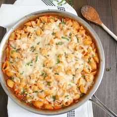 a pan filled with pasta and sauce on top of a wooden table