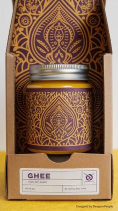 an open box with a purple and gold design on it's lid, next to a jar of honey