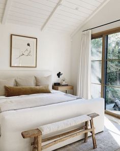 a bedroom with white walls and wooden furniture in front of a sliding glass door that leads to an outside deck