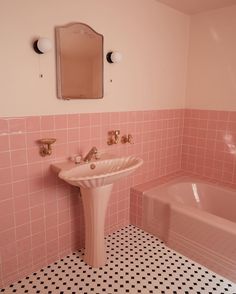 a bathroom with pink tiles and black and white flooring, including a pedestal sink