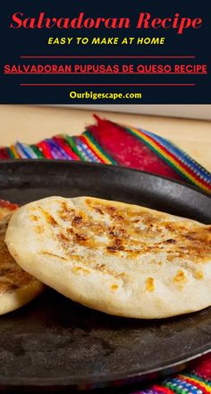 two flat breads sitting on top of a black plate next to a colorful cloth