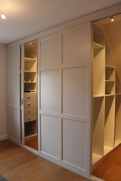 an empty room with white closets and shelves in the corner, along with wood flooring