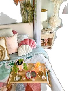 a bed with many pillows on top of it next to a table filled with other items