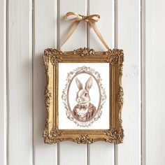 a painting hanging on the wall with a bow around it's neck and an image of a rabbit in a frame