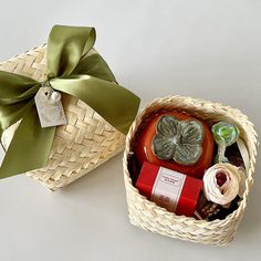 two baskets with different items in them on a white surface, one has a green ribbon and the other has a bow