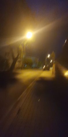 blurry image of street lights at night with cars driving on the road behind them