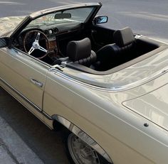 the interior of a convertible car parked on the side of the road with its door open