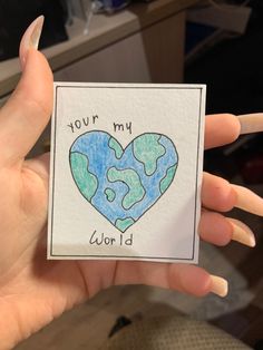 someone is holding up a card with the earth in the shape of a heart that says, your my world