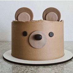 a cake decorated to look like a bear's head with ears and eyes on top