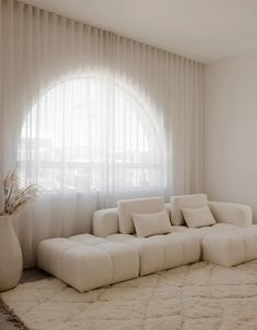 a large white couch sitting in front of a window