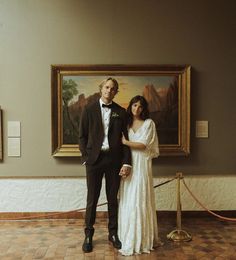 a man and woman standing next to each other in front of a painting