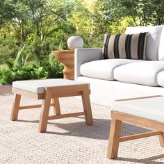 a white couch sitting on top of a wooden floor next to a chair and ottoman