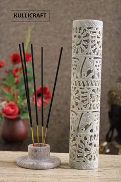 a white vase sitting on top of a wooden table next to reeds and flowers