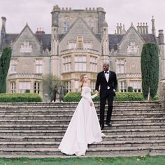 a bride and groom walking up some steps in front of a large building with stairs