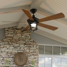 a ceiling fan mounted on the side of a brick wall next to a fire place