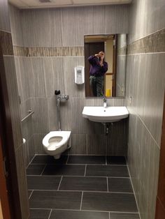 a man taking a selfie in a bathroom mirror next to a toilet and sink