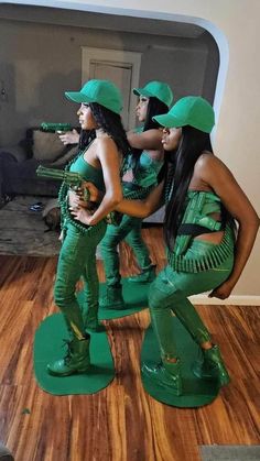 three women in green outfits are standing on the floor and one is holding a guitar