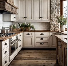 a kitchen with white cabinets and wood floors is pictured in this image, there are potted plants on the counter