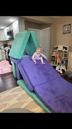 a baby sitting on top of a purple slide