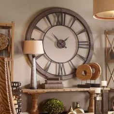 a large clock mounted to the side of a wall next to a table and chair