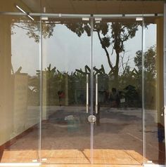 an open glass door with the reflection of trees in it