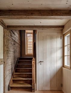 an open door leading to a wooden staircase in a home with wood floors and walls