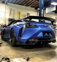 a blue sports car parked in a garage with its hood up and the top down