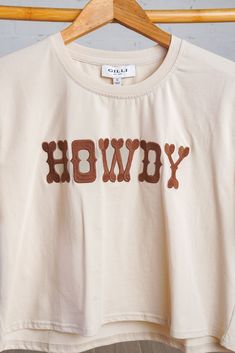 Update your casual style with our playful yet versatile Howdy Tee. Featuring bold brown stitching and "Howdy" lettering across the front, this shirt adds a touch of fun and personality to any outfit. The soft, lightweight material ensures a comfortable and breathable fit with just the right amount of stretch. Pair it with denim or a skirt for a concert friendly look. Fits true to size. Crop style in cream. 95% Cotton, 5% Spandex Summer Graphic Tee Shirt In Brown, Crop Style, Cropped Style, New Arrival Dress, A Skirt, Savannah Chat, Casual Style, Midi Skirt, Stitching