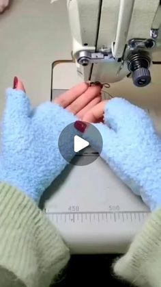 someone using a sewing machine to sew gloves on their hands and the mitts are blue