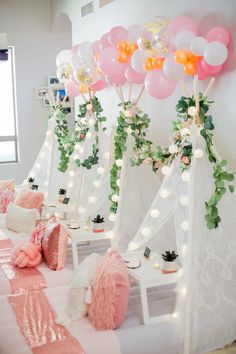 balloons and garlands are set up on the table for a party with pink and white decor