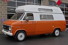 an orange and white van parked in front of a building