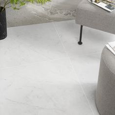 a white marble tile floor in a living room with grey chairs and a plant on the side