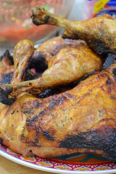 a whole chicken on a plate with other food items in the backgroung