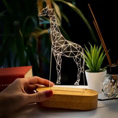 a person is holding a paper cut out of a giraffe on a table