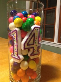 a glass filled with lots of colorful balloons and numbers on top of each one's birthday candles