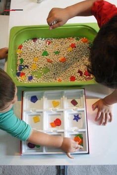 two children are playing with their toys on the table in front of a green tray