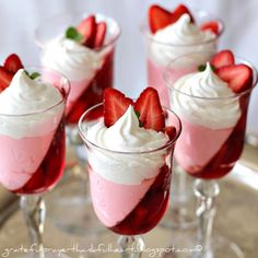 four desserts with strawberries and whipped cream in small glasses on a silver tray