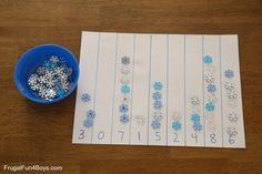 the snowflakes are on paper next to a blue bowl with silver and white beads