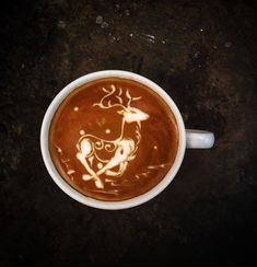 a cup of hot chocolate with a drawing of a deer on the foam in it