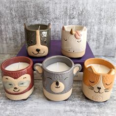 four ceramic mugs with animals on them sitting on a table next to each other