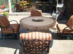 an outdoor fire pit surrounded by chairs and tables