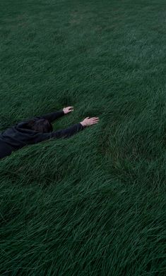 a person laying in the grass with their arms out