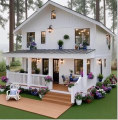 a white house with lots of windows and flowers on the front porch, next to a wooden deck